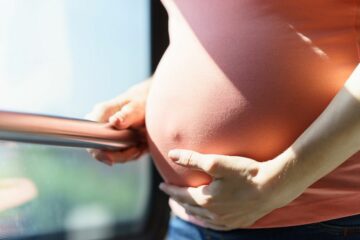 vrouw staat rechtop met bandenpijn tijdens de zwangerschap