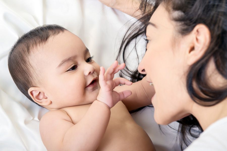 Baby van 9 weken oud onderzoekt de mond van zijn moeder