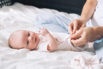moeder trekt haar baby een rompertje aan