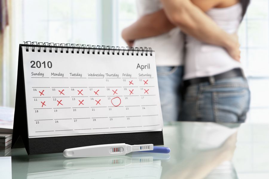Man en vrouw knuffelen elkaar op de achtergrond en zwangerschapskalender op voorgrond
