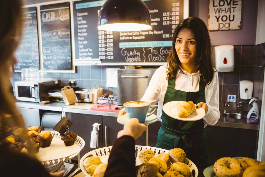 Zwangere vrouw serveert koffie in een café