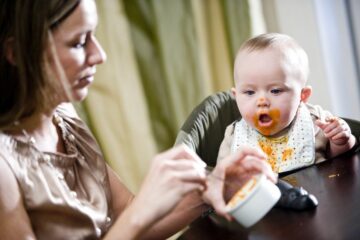 Moeder voert haar baby eerste hapjes