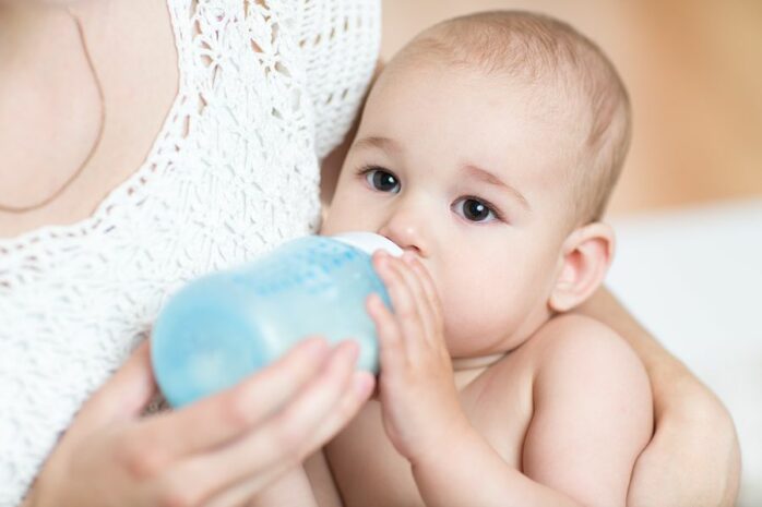 Moeder geeft baby met obstipatie fles
