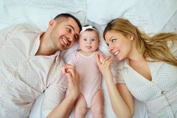 Ouders en baby met goede hechting liggen op bed gelukkig te zijn met elkaar