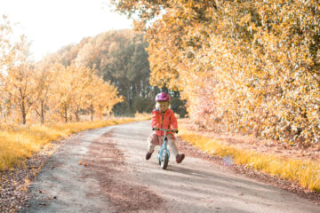 Kindje speelt met loopfiets op bospad