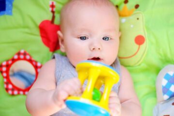 baby ligt op speelkleed met speeltje
