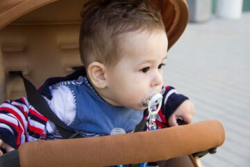 baby met speen in wandelwagen