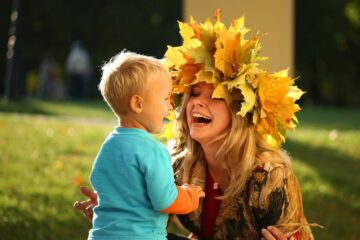 Moeder en peuter spelen met bladeren in vrije tijd