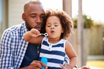 Vader blaast bellen met dochter: positieve aandacht in de opvoeding