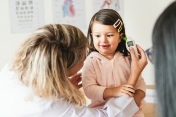 dokter meet temperatuur met oorthermometer bij meisje