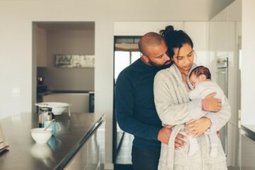Ouders staan in keuken met pasgeboren baby te knuffelen op eerste dag thuis