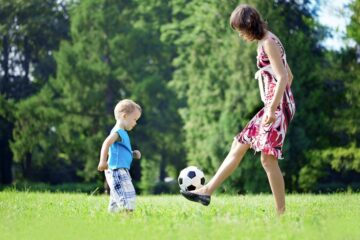 Peuter en moeder spelen samen buiten met de voetbal