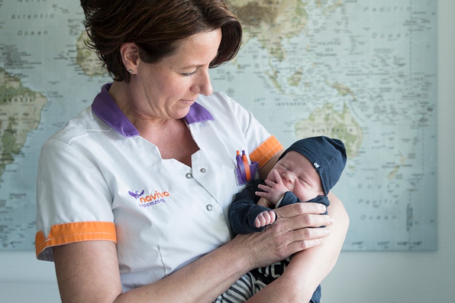 Kraamverzorgende baby met mutsje