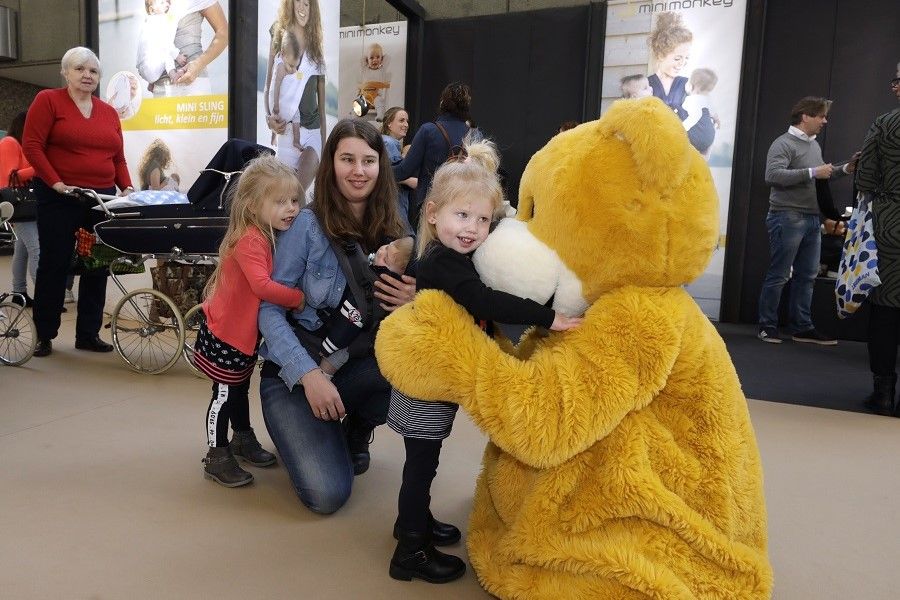 Sfeerbeeld Negenmaandenbeurs, meisje knuffelt berenmascotte