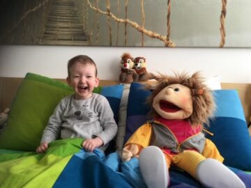 Peuter peelgoed: meisje zit in bed met een handpop