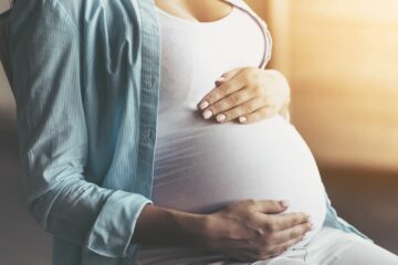 Zwangere vrouw houdt buik vast en denkt na over uitvaartverzekering tijdens de zwangerschap