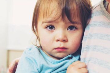 Verdrietig meisje wordt getroost door ouder na scheiden van haar ouders