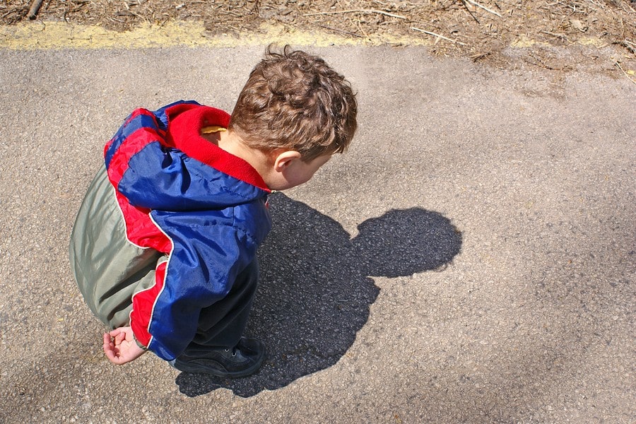 Kind van 2 jaar kijkt naar eigen schaduw