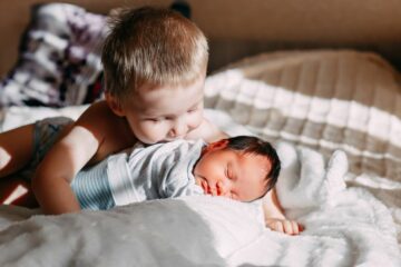 Peuter knuffelt met zijn nieuw zusje en is niet jaloers