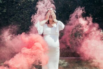 Vrouw wordt tijdens Gender reveal omringd door roze rook