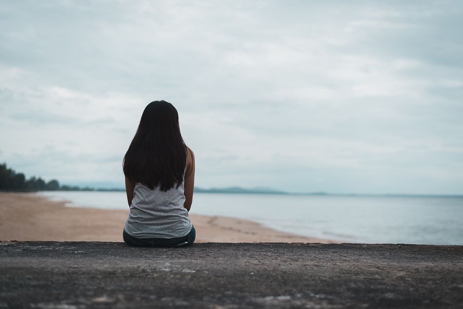 Vrouw zit op het strand in haar eentje