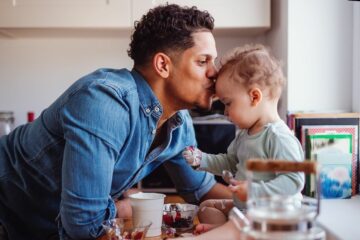 Vader en baby eten samen blauwe bessen, waarbij risico op verstikking bestaat