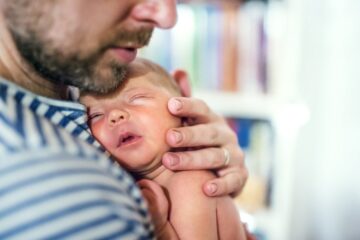 Vader draagt baby met korte stoere jongensnaam