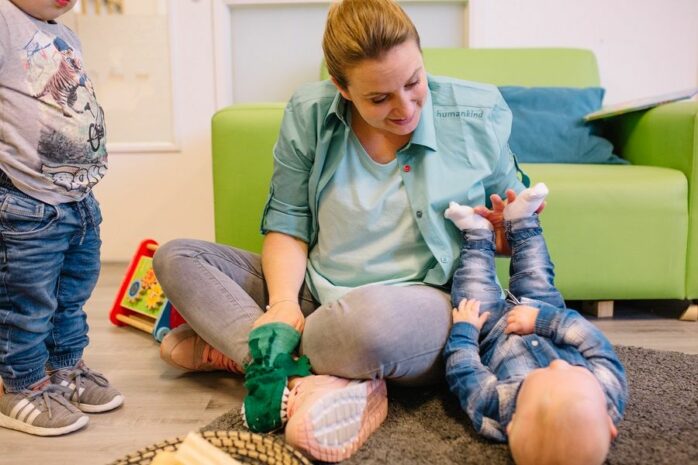 Begeleidster van het kinderdagverblijf speelt met kindje