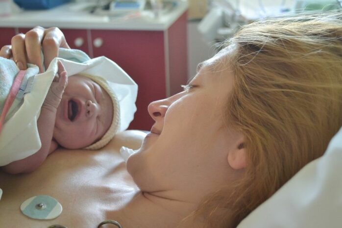 Pas bevallen vrouw bewondert haar pasgeboren baby