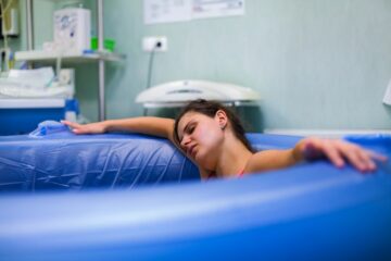 Vrouw ligt in bad te bevallen