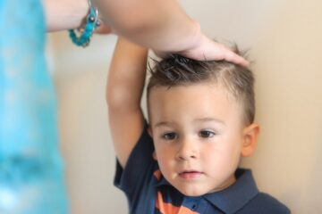 Jongetje staat tegen muur en moeder meet zijn lengte om de groeicurve bij te houden