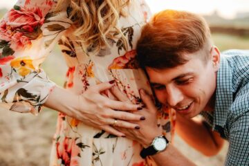 Zwanger stel verwondert zich over zwangerschapsmythes terwijl man naar buik luistert