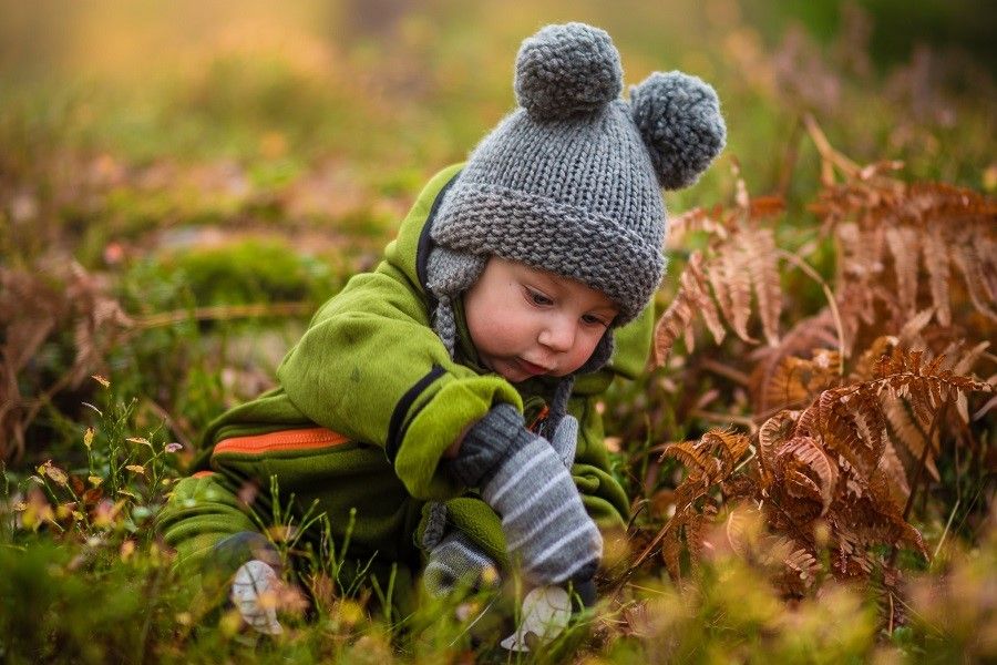 Peuter met muts is aan het spelen in de natuur