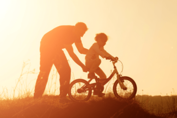 Vader leert jongetje fietsen op kinderfiets
