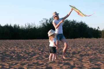 Moeder en dochter spelen samen met een vlieger op het strand