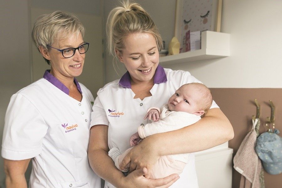 Kraamverzorgende van Naviva levert kraamzorg, houdt baby vast
