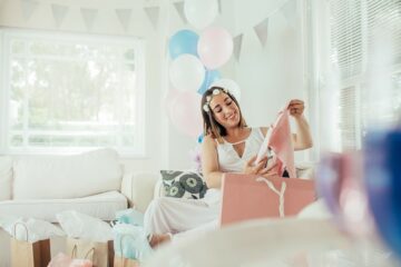 Zwangere vrouw pakt een babyshower-cadeau uit