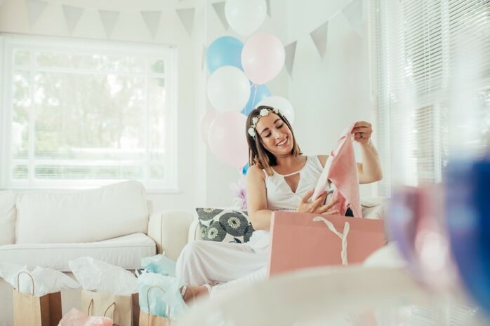 Zwangere vrouw pakt een babyshower-cadeau uit