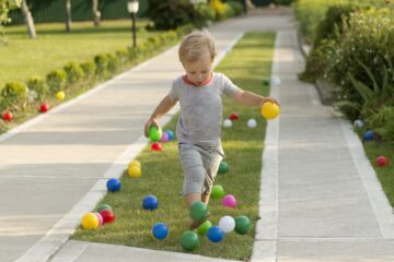 Jongetje speelt tuinspelletjes en houdt een ballenkermis met gekleurde balletjes