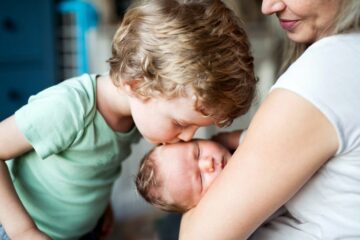grote broer geeft tweede kind een kusje