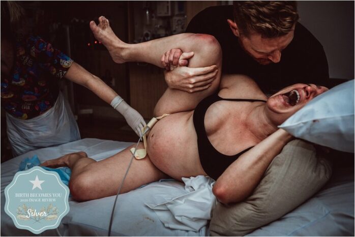 Man ondersteunt zijn vrouw die het uitschreeuwt tijdens de bevalling