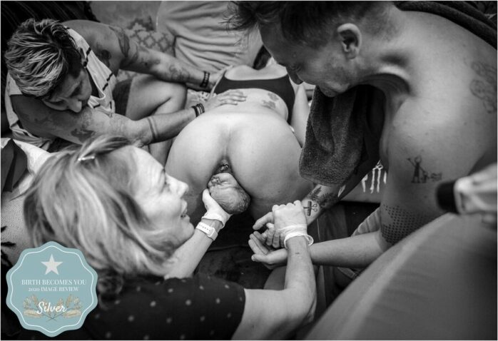 Vrouw zit op handen en voeten en het hoofdje van haar baby komt er al uit