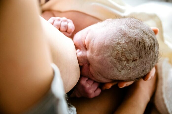 Close-up van basgeboren baby aan de borst van zijn moeder