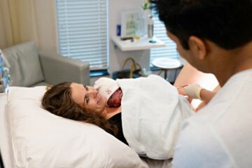 Trotse moeder kijkt stralend naar haar partner met baby op de borst