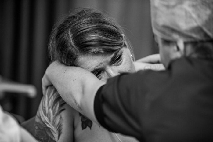 Vrouw die aan het bevallen is is in tranen terwijl haar partner haar ondersteunt