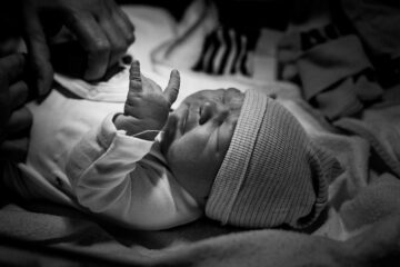 Pasgeboren baby houdt zijn handje als een rocker