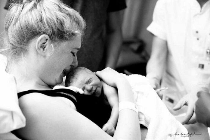 Pasbevallen vrouw houdt haar baby huilend vast op de borst