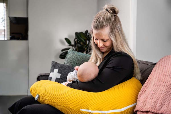 Vrouw voedt haar baby op een voedingskussen