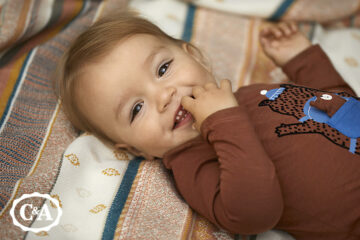 kindje lacht en draagt babykleding C&A