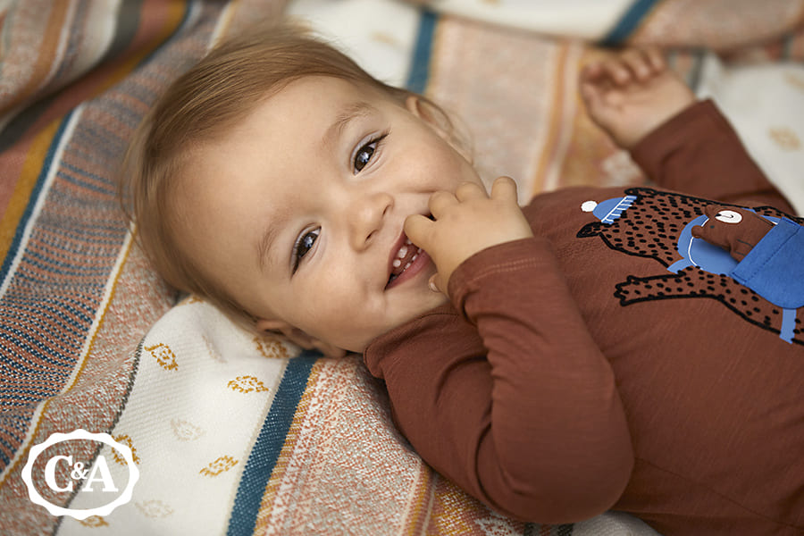 kindje lacht en draagt babykleding C&A